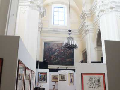 Non ci resta a questo punto che entrare, per trovarci davanti a uno spettacolo inaspettato. I paramenti sacri, le statue, i dipinti, sono infatti tutti celati dietro pannelli in cartone bianchi su cui sono esposte opere di arte contemporanea. Santa Teresa sta infatti ospitando una mostra